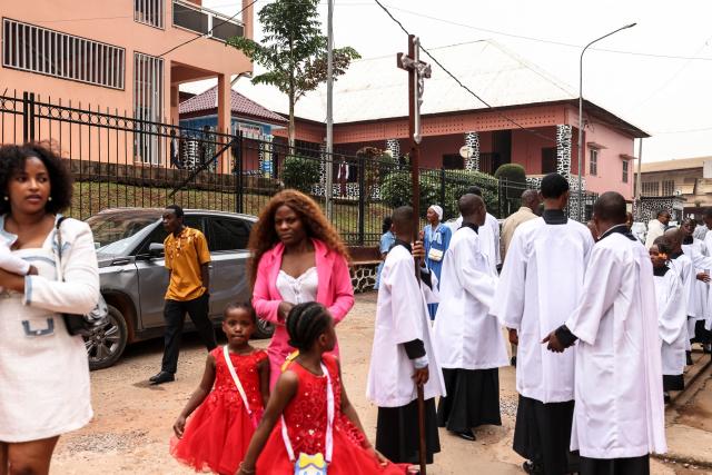 Altar servers and worshippers gather in the courtyard of Notre Dame des Victoires Cathedral before the start of Easter Mass in Yaounde on April 5, 2026. (Photo by Daniel BELOUMOU OLOMO / AFP)