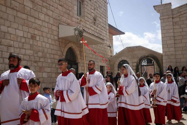 Alter servers walk during the Palm Sunday mass at the Latin Church in the mostly Christian town of Taybeh, in the Israeli-occupied West Bank on Orthodox Palm Sunday on April 5, 2026. (Photo by Zain JAAFAR / AFP)