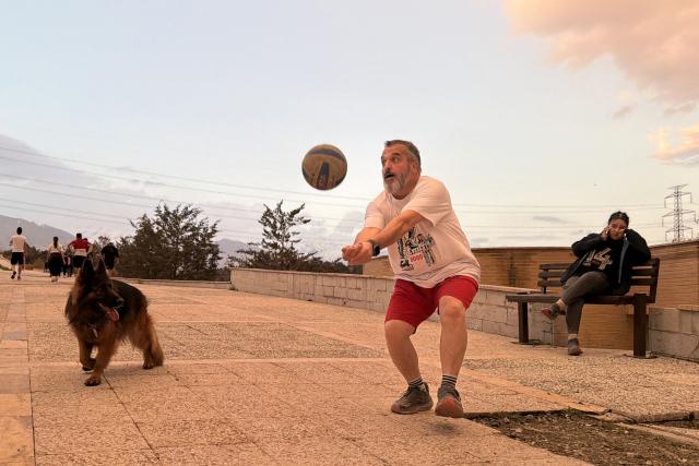 A man plays along with his dog at the Pardisan Park in Tehran on April 5, 2026. The war, which erupted on February 28, 2026 with US-Israeli strikes on Iran, has engulfed the Middle East and convulsed the global economy. (Photo by ATTA KENARE / AFP)