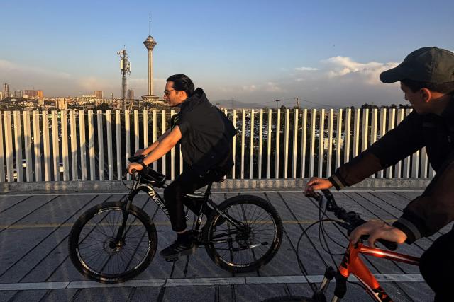 Men ride their bicycles through the Pardisan Park in Tehran on April 5, 2026. The war, which erupted on February 28, 2026 with US-Israeli strikes on Iran, has engulfed the Middle East and convulsed the global economy. (Photo by ATTA KENARE / AFP)