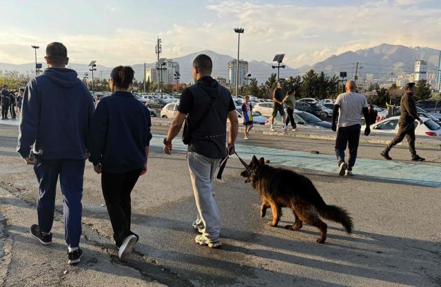 A family along with their dog, walks through the Pardisan Park in Tehran on April 5, 2026. The war, which erupted on February 28, 2026 with US-Israeli strikes on Iran, has engulfed the Middle East and convulsed the global economy. (Photo by ATTA KENARE / AFP)