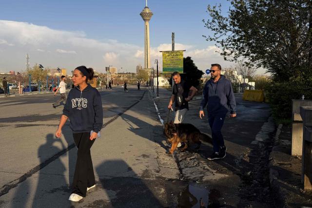 A family along with their dog, walks through the Pardisan Park in Tehran on April 5, 2026. The war, which erupted on February 28, 2026 with US-Israeli strikes on Iran, has engulfed the Middle East and convulsed the global economy. (Photo by ATTA KENARE / AFP)