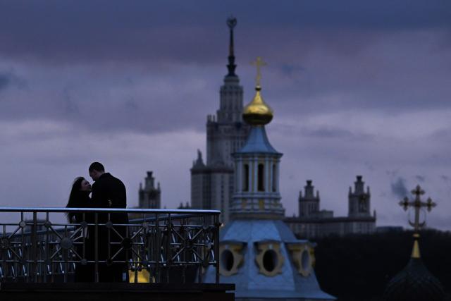 A couple hugs on an observation deck near the Russian Academy of Sciences overlooking the Moscow State University buildind and Saint Andrew's Church in Moscow, on April 5, 2026. (Photo by Igor IVANKO / AFP)