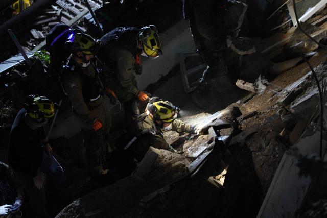 Israeli search and rescue personnel work on the site of a residential building that was destroyed by an Iranian strike in the neighbourhood in Haifa on April 5, 2026. Israeli firefighters were searching for three missing people in the rubble of a residential building in the northern city of Haifa after it was struck by an Iranian missile April 5. The direct hit on a seven-storey building tore through parts of the structure, injuring four people, the military and rescue services said. (Photo by Ilia YEFIMOVICH / AFP) / 