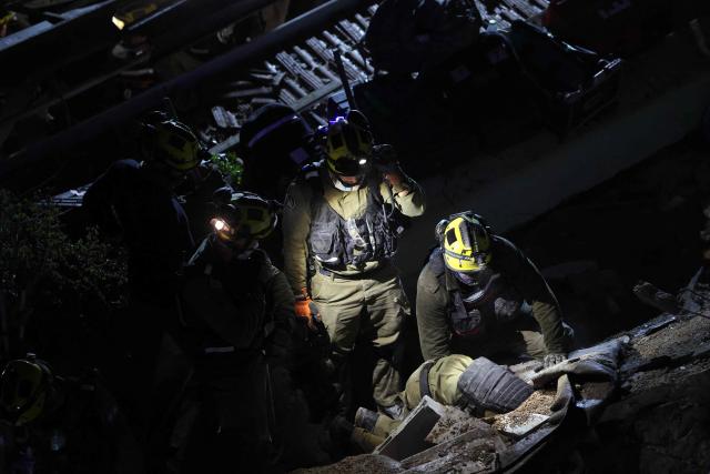 Israeli search and rescue personnel work on the site of a residential building that was destroyed by an Iranian strike in the neighbourhood in Haifa on April 5, 2026. Israeli firefighters were searching for three missing people in the rubble of a residential building in the northern city of Haifa after it was struck by an Iranian missile April 5. The direct hit on a seven-storey building tore through parts of the structure, injuring four people, the military and rescue services said. (Photo by Ilia YEFIMOVICH / AFP) / 