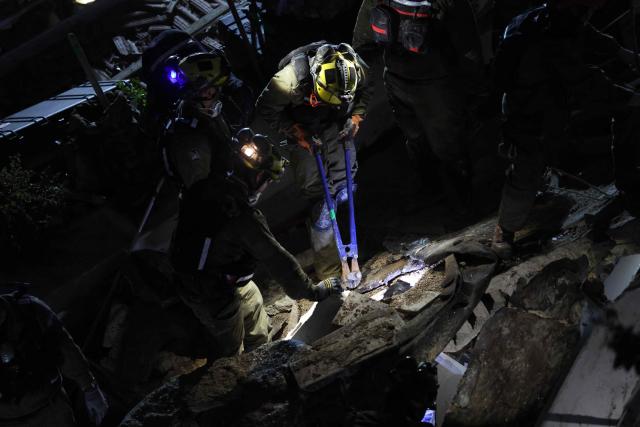 Israeli search and rescue personnel work on the site of a residential building that was destroyed by an Iranian strike in the neighbourhood in Haifa on April 5, 2026. Israeli firefighters were searching for three missing people in the rubble of a residential building in the northern city of Haifa after it was struck by an Iranian missile April 5. The direct hit on a seven-storey building tore through parts of the structure, injuring four people, the military and rescue services said. (Photo by Ilia YEFIMOVICH / AFP) / 