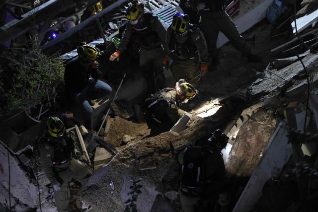 Israeli search and rescue personnel work on the site of a residential building that was destroyed by an Iranian strike in the neighbourhood in Haifa on April 5, 2026. Israeli firefighters were searching for three missing people in the rubble of a residential building in the northern city of Haifa after it was struck by an Iranian missile April 5. The direct hit on a seven-storey building tore through parts of the structure, injuring four people, the military and rescue services said. (Photo by Ilia YEFIMOVICH / AFP) / 
