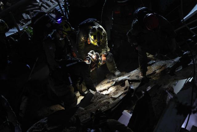 Israeli search and rescue personnel work on the site of a residential building that was destroyed by an Iranian strike in the neighbourhood in Haifa on April 5, 2026. Israeli firefighters were searching for three missing people in the rubble of a residential building in the northern city of Haifa after it was struck by an Iranian missile April 5. The direct hit on a seven-storey building tore through parts of the structure, injuring four people, the military and rescue services said. (Photo by Ilia YEFIMOVICH / AFP) / 