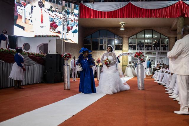 A bride walks down the aisle with the groom’s (unseen) first wife during the Easter 2026 mass wedding ceremony at the International Pentecost Holiness Church (IPHC) headquarters in Zuurbekom, Westonaria, on April 5, 2026. (Photo by ILARIA FINIZIO / AFP)