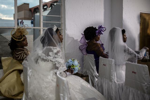 Brides sit with their grooms’ first wives as they wait to enter the church during the Easter 2026 mass wedding ceremony at the International Pentecost Holiness Church (IPHC) headquarters in Zuurbekom, Westonaria, on April 5, 2026. (Photo by ILARIA FINIZIO / AFP)