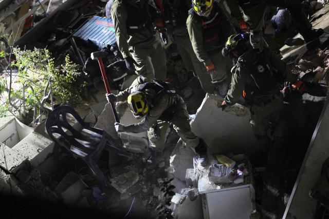 Israeli search and rescue personnel work at the site of a residential building destroyed in an Iranian strike in the northern city of Haifa on April 5, 2026. Israeli firefighters were searching for three missing people in the rubble of a residential building in the northern city of Haifa after it was struck by an Iranian missile April 5. The direct hit on a seven-storey building tore through parts of the structure, injuring four people, the military and rescue services said. (Photo by Ilia YEFIMOVICH / AFP) / 