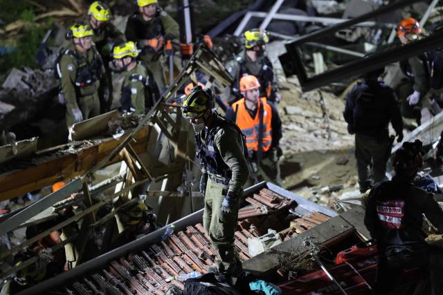 Israeli search and rescue personnel work at the site of a residential building destroyed in an Iranian strike in the northern city of Haifa on April 5, 2026. Israeli firefighters were searching for three missing people in the rubble of a residential building in the northern city of Haifa after it was struck by an Iranian missile April 5. The direct hit on a seven-storey building tore through parts of the structure, injuring four people, the military and rescue services said. (Photo by Ilia YEFIMOVICH / AFP) / 