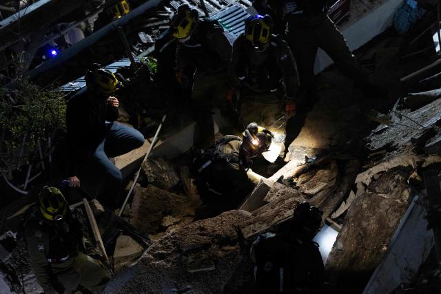 Israeli search and rescue personnel work at the site of a residential building destroyed in an Iranian strike in the northern city of Haifa on April 5, 2026. Israeli firefighters were searching for three missing people in the rubble of a residential building in the northern city of Haifa after it was struck by an Iranian missile April 5. The direct hit on a seven-storey building tore through parts of the structure, injuring four people, the military and rescue services said. (Photo by Ilia YEFIMOVICH / AFP) / 