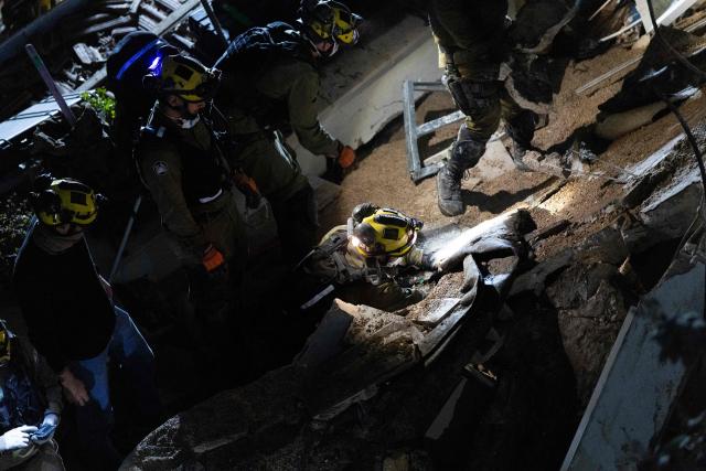 Israeli search and rescue personnel work at the site of a residential building destroyed in an Iranian strike in the northern city of Haifa on April 5, 2026. Israeli firefighters were searching for three missing people in the rubble of a residential building in the northern city of Haifa after it was struck by an Iranian missile April 5. The direct hit on a seven-storey building tore through parts of the structure, injuring four people, the military and rescue services said. (Photo by Ilia YEFIMOVICH / AFP) / 