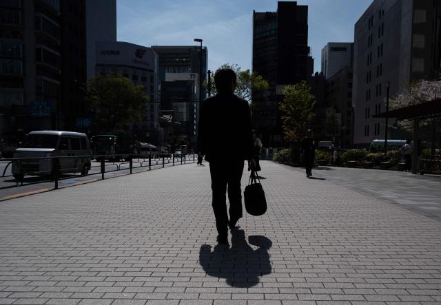 A man carries a briefcase as he walks past office buildings in Tokyo on April 6, 2026. (Photo by Andrew CABALLERO-REYNOLDS / AFP)