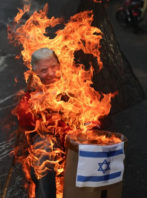 An effigy depicting US President Donald Trump and an Israeli flag burn during the Burning of Judas ritual as part of Easter celebrations on a street in the 23 de Enero neighborhood in Caracas on April 5, 2026. (Photo by Jesus VARGAS / AFP)