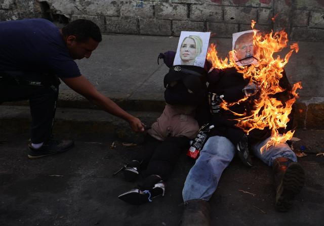 A man sets fire to an effigy depicting US President Donald Trump burns during the Burning of Judas ritual as part of Easter celebrations on a street in the 23 de Enero neighborhood in Caracas on April 5, 2026. (Photo by JESUS VARGAS / AFP)