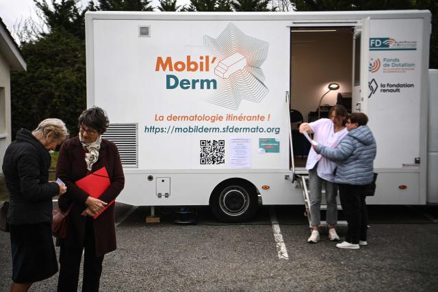 Patients wait ahead of an appointment with a dermatologist in an itinerant truck as part of the Mobil Derm project supported by the Societe Francaise de Dermatologie (French Dermatology Society) at a parking lot in Lafox, south-western France, on April 2, 2026. As in the rest of France, patients suffering from skin diseases are facing significant delays in receiving care in Nouvelle-Aquitaine, with loss of chances in the most serious cases. In Lafox, 25 patients a day enter the few square meters of the mobile clinic, where a dermatologist from the Basque Country has come for two days to carry out consultations in her free time  a pioneering system in France intended to compensate for the shortage of dermatologists and address medical deserts. (Photo by Christophe ARCHAMBAULT / AFP)
