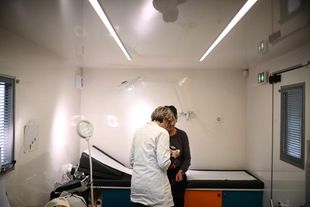 Dermatologist Blandine De Carrere conducts a consultation in an itinerant truck as part of the Mobil Derm project supported by the Societe Francaise de Dermatologie (French Dermatology Society) at a parking lot in Lafox, south-western France, on April 2, 2026. As in the rest of France, patients suffering from skin diseases are facing significant delays in receiving care in Nouvelle-Aquitaine, with loss of chances in the most serious cases. In Lafox, 25 patients a day enter the few square meters of the mobile clinic, where a dermatologist from the Basque Country has come for two days to carry out consultations in her free time  a pioneering system in France intended to compensate for the shortage of dermatologists and address medical deserts. (Photo by Christophe ARCHAMBAULT / AFP)