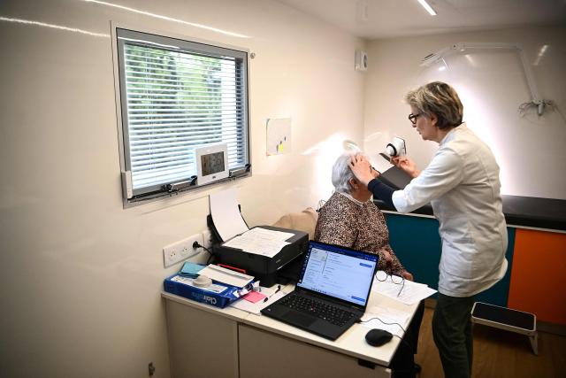 Dermatologist Blandine De Carrere conducts a consultation in an itinerant truck as part of the Mobil Derm project supported by the Societe Francaise de Dermatologie (French Dermatology Society) at a parking lot in Lafox, south-western France, on April 2, 2026. As in the rest of France, patients suffering from skin diseases are facing significant delays in receiving care in Nouvelle-Aquitaine, with loss of chances in the most serious cases. In Lafox, 25 patients a day enter the few square meters of the mobile clinic, where a dermatologist from the Basque Country has come for two days to carry out consultations in her free time  a pioneering system in France intended to compensate for the shortage of dermatologists and address medical deserts. (Photo by Christophe ARCHAMBAULT / AFP)
