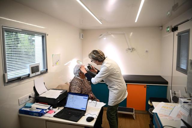 Dermatologist Blandine De Carrere conducts a consultation in an itinerant truck as part of the Mobil Derm project supported by the Societe Francaise de Dermatologie (French Dermatology Society) at a parking lot in Lafox, south-western France, on April 2, 2026. As in the rest of France, patients suffering from skin diseases are facing significant delays in receiving care in Nouvelle-Aquitaine, with loss of chances in the most serious cases. In Lafox, 25 patients a day enter the few square meters of the mobile clinic, where a dermatologist from the Basque Country has come for two days to carry out consultations in her free time  a pioneering system in France intended to compensate for the shortage of dermatologists and address medical deserts. (Photo by Christophe ARCHAMBAULT / AFP)