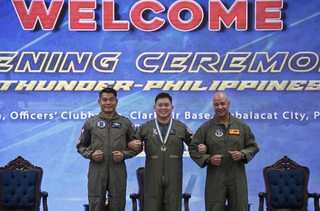 US Air Force Brigadier General Phillip Mallory (R), Pacific Air Force head of delegation, Philippine Major General Dennis Estrella (C), commander of Air logistics command and Philippine Brigadier General Angelito Retuta (L) commander of Tactical operation wing of Northern Luzon join hands during the opening ceremony of the COPE Thunder exercise at Clark air base in Angeles city, Pampanga province on April 6, 2026. (Photo by Ted ALJIBE / AFP)