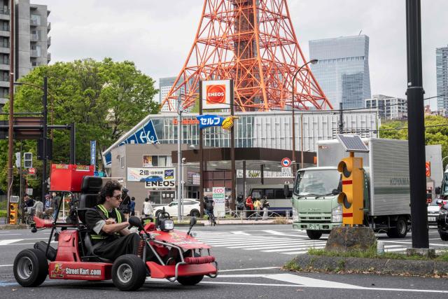 A foreign tourist drives a go-kart drives past a gas station in Tokyo on April 6, 2026. (Photo by Yuichi YAMAZAKI / AFP)