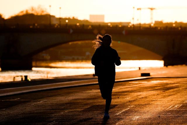 A jogger runs near the Seine river at sunrise in Paris on April 6, 2026. (Photo by Kenzo TRIBOUILLARD / AFP)