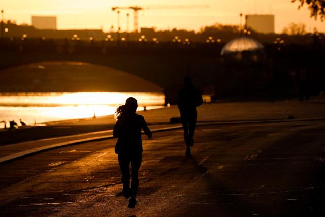 A jogger runs near the Seine river at sunrise in Paris on April 6, 2026. (Photo by Kenzo TRIBOUILLARD / AFP)