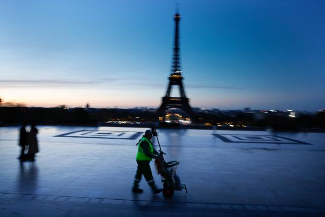 A cleaning worker walks with a trolley at the Trocadero in front of the Eiffel Tower at sunrise in Paris on April 6, 2026. (Photo by Kenzo TRIBOUILLARD / AFP)