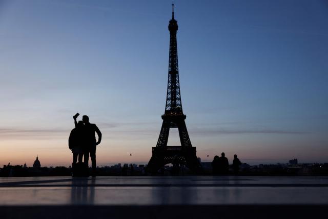 TOPSHOT - Two people take a selfie at the Trocadero in front of the Eiffel Tower at sunrise in Paris on April 6, 2026. (Photo by Kenzo TRIBOUILLARD / AFP)