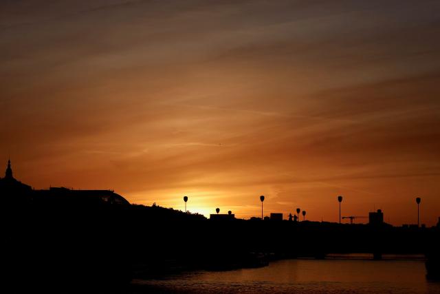 The sun rises over the Seine river in Paris on April 6, 2026. (Photo by Kenzo TRIBOUILLARD / AFP)