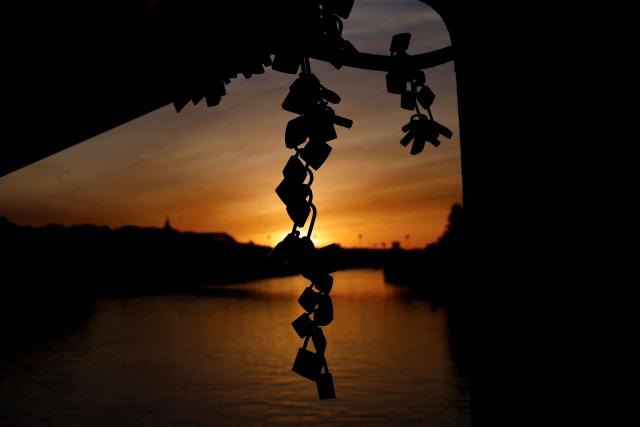 Love padlocks are attached on the Debilly footbridge over the Seine river at sunrise in Paris, on April 6, 2026. (Photo by Kenzo TRIBOUILLARD / AFP)