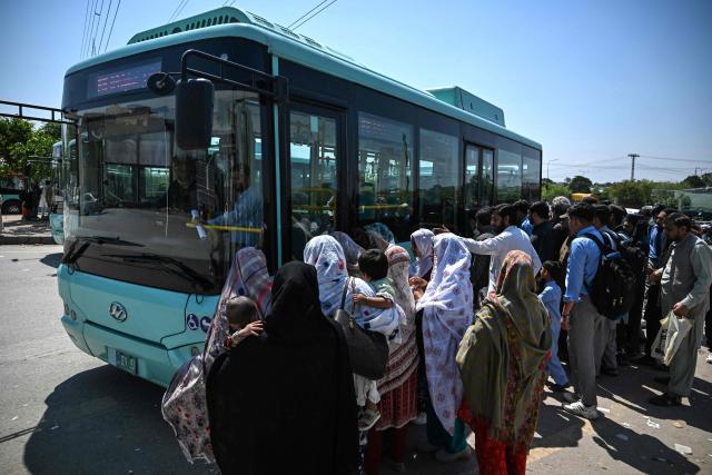 Commuters rush to board a free state-run public bus in Islamabad on April 6, 2026. State-run public transport in Pakistan's capital and most populous province will be free for the coming month, officials said on April 3, after the government drastically raised fuel prices due to the Iran war. (Photo by Aamir QURESHI / AFP)