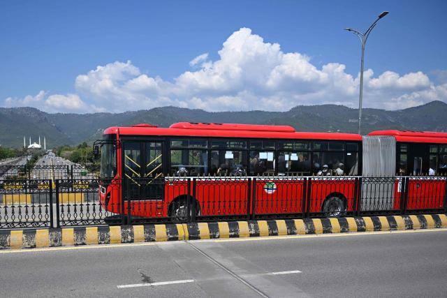 A free state-run public bus travel along a road in Islamabad on April 6, 2026. State-run public transport in Pakistan's capital and most populous province will be free for the coming month, officials said on April 3, after the government drastically raised fuel prices due to the Iran war. (Photo by Aamir QURESHI / AFP)