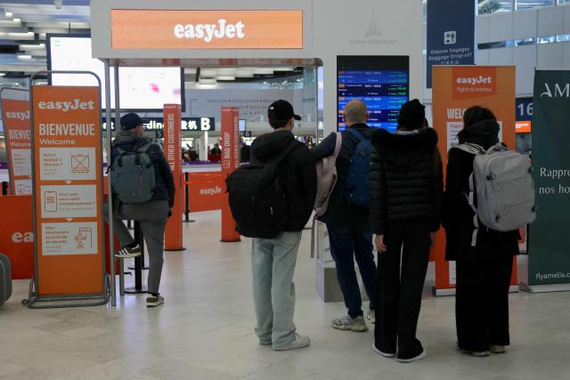 Passengers look at an information board at the EasyJet check-in counter while some of the airline's staff are on strike at Orly Airport, in the Paris suburbs, on April 6, 2026. (Photo by Thomas SAMSON / AFP)