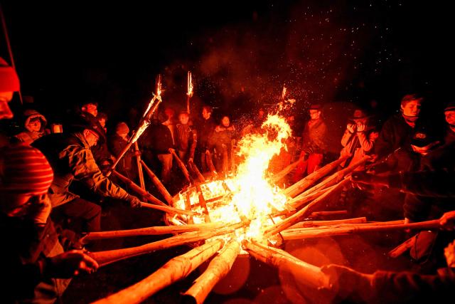 Participants light torches for the Easter fire on a hill in Attendorn, western Germany on April 5, 2026. Easter fires are traditionally lit all over Germany on Holy Saturday and Easter Sunday. In Attendorn, Easter fires with huge crosses are burned on four hills. In addition, burning torches are waved, with which fire circles are painted in the air. (Photo by Ina FASSBENDER / AFP)