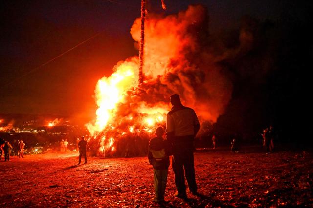 TOPSHOT - Participants watch the Easter fire on a hill in Attendorn, western Germany on April 5, 2026. Easter fires are traditionally lit all over Germany on Holy Saturday and Easter Sunday. In Attendorn, Easter fires with huge crosses are burned on four hills. In addition, burning torches are waved, with which fire circles are painted in the air. (Photo by Ina FASSBENDER / AFP)