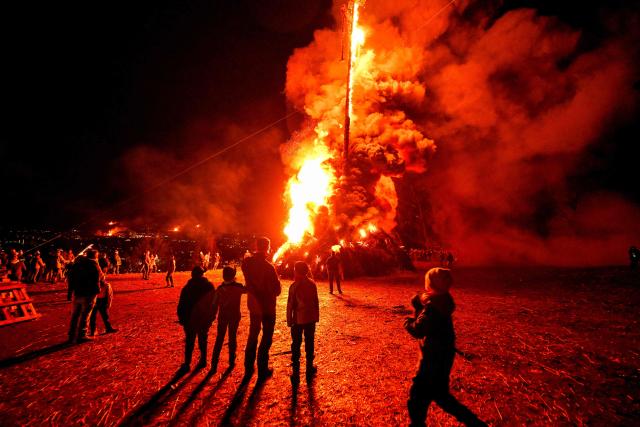 Participants watch the Easter fire on a hill in Attendorn, western Germany on April 5, 2026. Easter fires are traditionally lit all over Germany on Holy Saturday and Easter Sunday. In Attendorn, Easter fires with huge crosses are burned on four hills. In addition, burning torches are waved, with which fire circles are painted in the air. (Photo by Ina FASSBENDER / AFP)