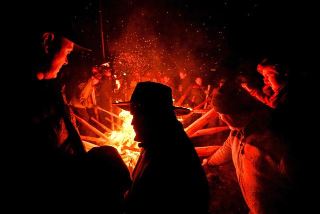 Participants light torches for the Easter fire on a hill in Attendorn, western Germany on April 5, 2026. Easter fires are traditionally lit all over Germany on Holy Saturday and Easter Sunday. In Attendorn, Easter fires with huge crosses are burned on four hills. In addition, burning torches are waved, with which fire circles are painted in the air. (Photo by Ina FASSBENDER / AFP)