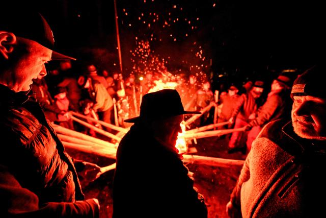 Participants light torches for the Easter fire on a hill in Attendorn, western Germany on April 5, 2026. Easter fires are traditionally lit all over Germany on Holy Saturday and Easter Sunday. In Attendorn, Easter fires with huge crosses are burned on four hills. In addition, burning torches are waved, with which fire circles are painted in the air. (Photo by Ina FASSBENDER / AFP)