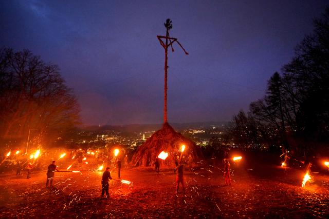 Participants wave burning torches before lighting the Easter fire on a hill in Attendorn, western Germany on April 5, 2026. Easter fires are traditionally lit all over Germany on Holy Saturday and Easter Sunday. In Attendorn, Easter fires with huge crosses are burned on four hills. In addition, burning torches are waved, with which fire circles are painted in the air. (Photo by Ina FASSBENDER / AFP)