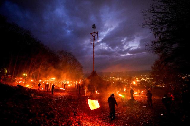 Participants wave burning torches before lighting the Easter fire on a hill in Attendorn, western Germany on April 5, 2026. Easter fires are traditionally lit all over Germany on Holy Saturday and Easter Sunday. In Attendorn, Easter fires with huge crosses are burned on four hills. In addition, burning torches are waved, with which fire circles are painted in the air. (Photo by Ina FASSBENDER / AFP)