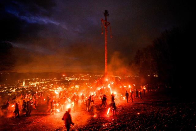 Participants light the Easter fire with burning torches on a hill in Attendorn, western Germany on April 5, 2026. Easter fires are traditionally lit all over Germany on Holy Saturday and Easter Sunday. In Attendorn, Easter fires with huge crosses are burned on four hills. In addition, burning torches are waved, with which fire circles are painted in the air. (Photo by Ina FASSBENDER / AFP)