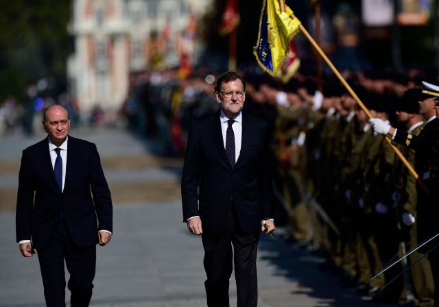 (FILES) Then Spanish Prime Minister Mariano Rajoy reviews the troups flanked by then Spanish Minister of Interior Jorge Fernandez Diaz (L) during a military ceremony in Madrid on November 6, 2015. The trial of former Spanish Interior Minister Jorge Fernandez Diaz starts on April 6, 2026 to answer for an alleged operation to prevent a former treasurer of his party - Spanish right-wing Partido Popular (Popular Party-PP)- from exposing corrupt practices. (Photo by Pierre-Philippe MARCOU / AFP)