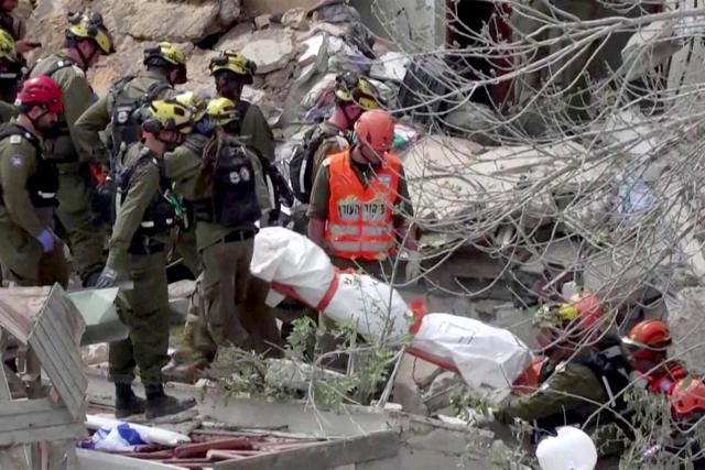 EDITORS NOTE: Graphic content / TOPSHOT - This frame grab from AFPTV footage shows Israeli rescue teams pulling out a bodies from the rubble of a residential building destroyed by an Iranian missile attack in the northern city of Haifa on April 6, 2026. Firefighters said two people had been killed and two more were missing under the rubble. Israeli strikes on April 6 killed the intelligence chief of Iran's Revolutionary Guards, as the Islamic republic on Monday defied threats from the US President to devastate civilian infrastructure if it does not reopen the Strait of Hormuz. (Photo by Jorge NOVOMINSKY / AFPTV / AFP) / 
