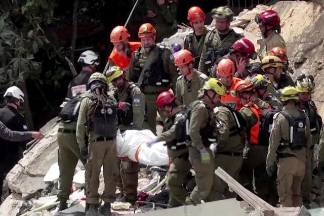 EDITORS NOTE: Graphic content / This frame grab from AFPTV footage shows Israeli rescue teams pulling out a bodies from the rubble of a residential building destroyed by an Iranian missile attack in the northern city of Haifa on April 6, 2026. Firefighters said two people had been killed and two more were missing under the rubble. Israeli strikes on April 6 killed the intelligence chief of Iran's Revolutionary Guards, as the Islamic republic on Monday defied threats from the US President to devastate civilian infrastructure if it does not reopen the Strait of Hormuz. (Photo by Jorge NOVOMINSKY / AFPTV / AFP) / 