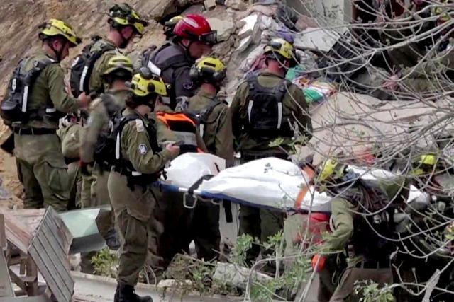 EDITORS NOTE: Graphic content / TOPSHOT - This frame grab from AFPTV footage shows Israeli rescue teams pulling out a bodies from the rubble of a residential building destroyed by an Iranian missile attack in the northern city of Haifa on April 6, 2026. Firefighters said two people had been killed and two more were missing under the rubble. Israeli strikes on April 6 killed the intelligence chief of Iran's Revolutionary Guards, as the Islamic republic on Monday defied threats from the US President to devastate civilian infrastructure if it does not reopen the Strait of Hormuz. (Photo by Jorge NOVOMINSKY / AFPTV / AFP) / 