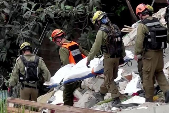 EDITORS NOTE: Graphic content / This frame grab from AFPTV footage shows Israeli rescue teams pulling out a bodies from the rubble of a residential building destroyed by an Iranian missile attack in the northern city of Haifa on April 6, 2026. Firefighters said two people had been killed and two more were missing under the rubble. Israeli strikes on April 6 killed the intelligence chief of Iran's Revolutionary Guards, as the Islamic republic on Monday defied threats from the US President to devastate civilian infrastructure if it does not reopen the Strait of Hormuz. (Photo by Jorge NOVOMINSKY / AFPTV / AFP) / 