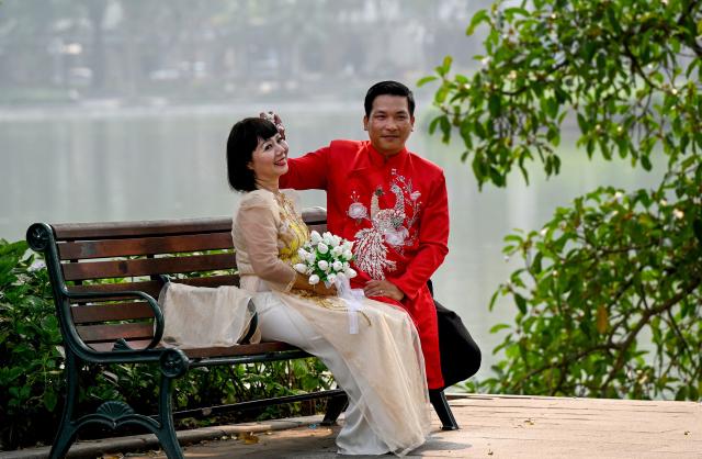 A couple poses for a photo at Hoan Kiem Lake in Hanoi on April 6, 2026. (Photo by Nhac NGUYEN / AFP)